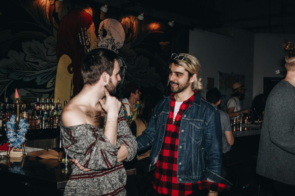 01 Well dressed crowd at a kink party in leather and harnesses with one underdressed man standing out